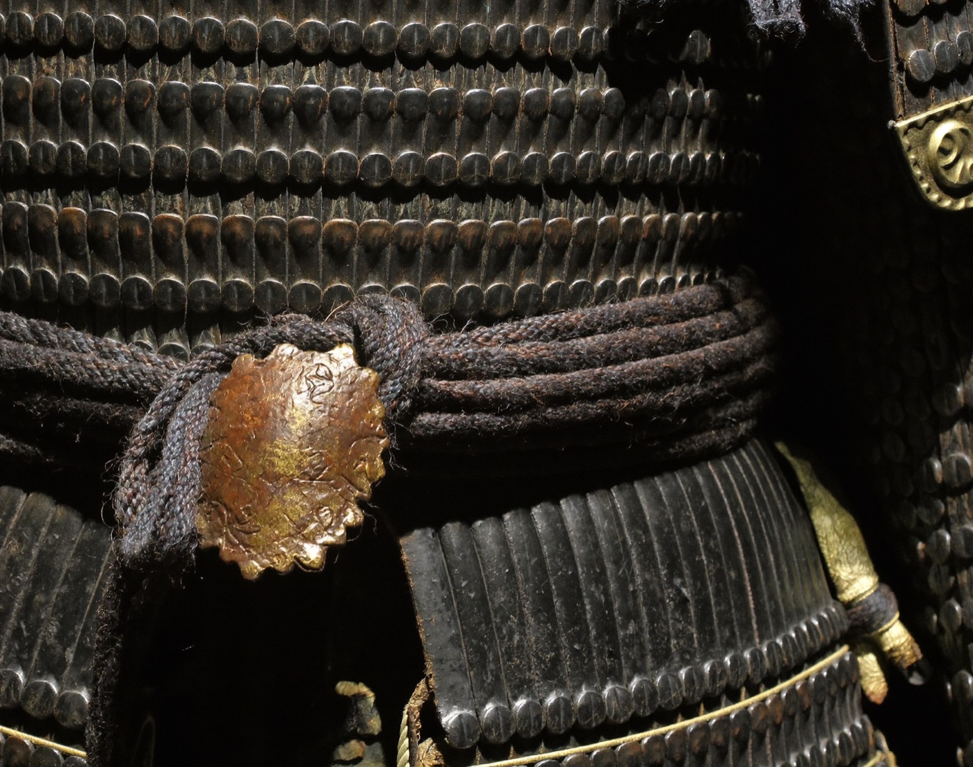 Macro view of lacquered armor scales bound with indigo silk cords