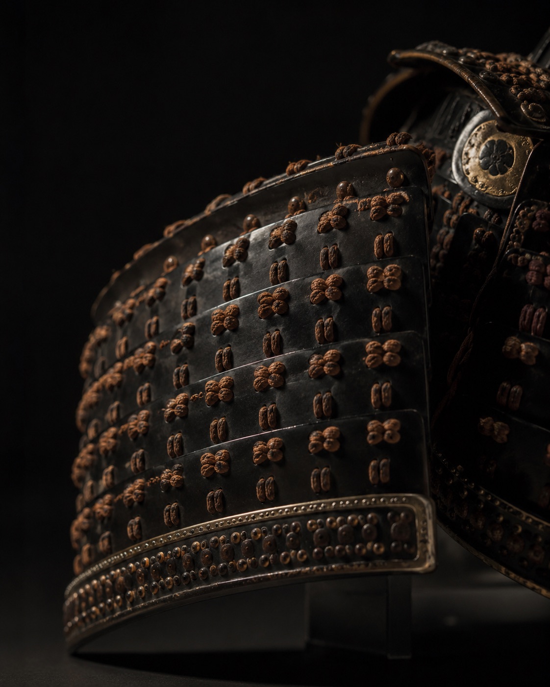 Black-lacquered ō-yoroi shoulder plates bound with warm brown silk knots and edged in aged gold